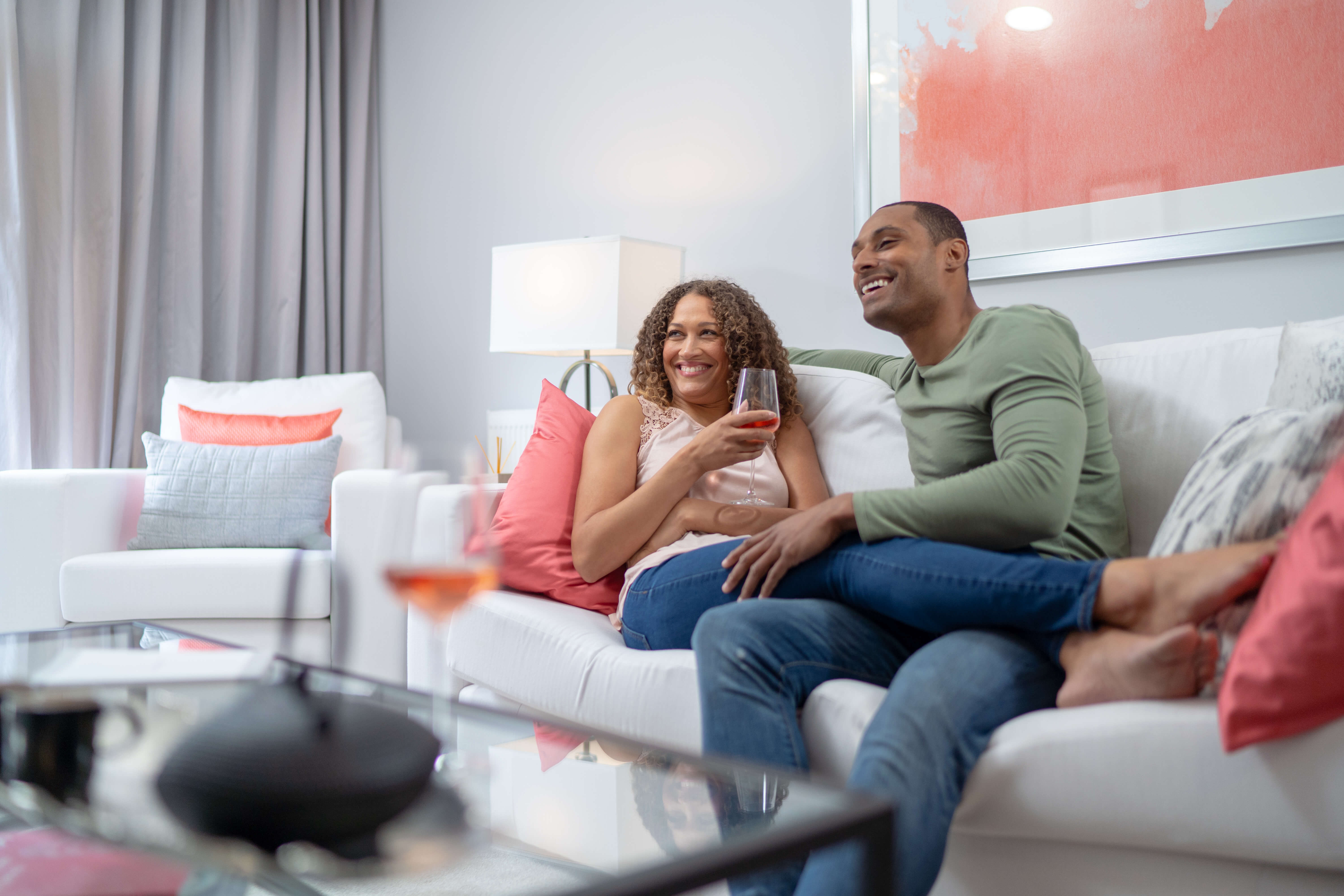 Couple sitting on the couch laughing drinking wine Couple sitting on the couch laughing drinking wine