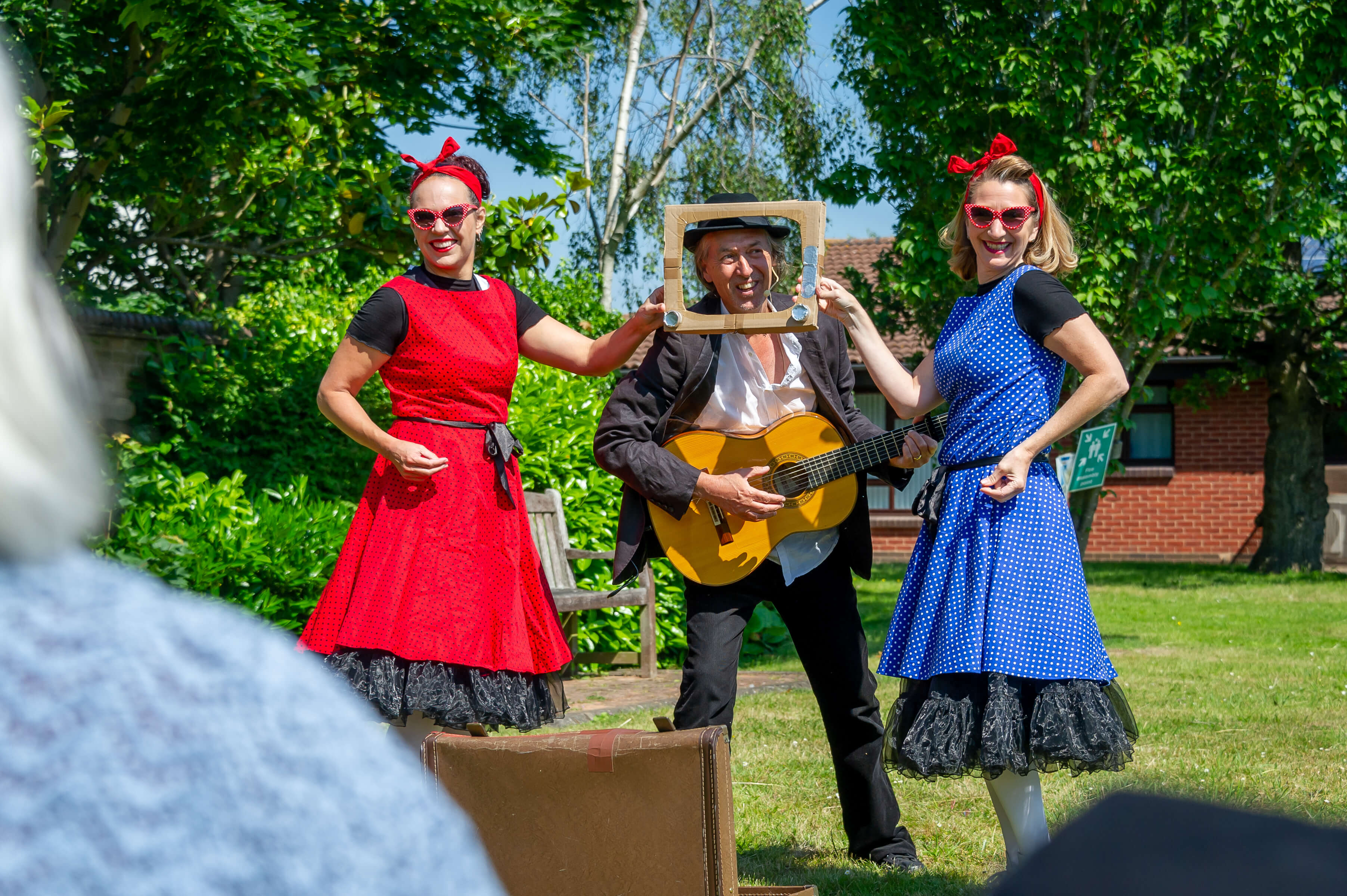 two ladies in dresses standing next to a man playing the guitar